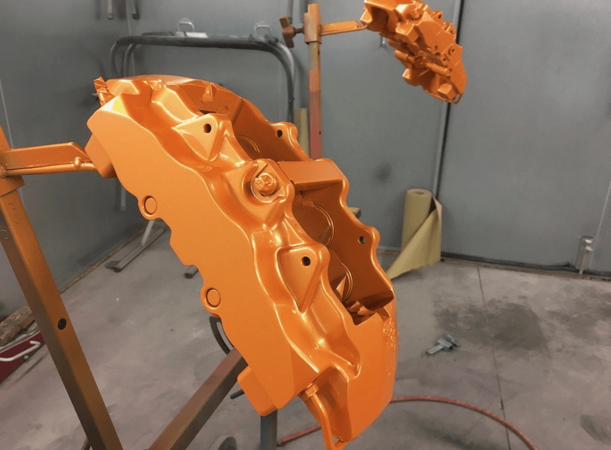 Orange painted brake calipers in the spray booth
